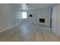 Open living room with cozy fireplace, light colored wood-look flooring, and sliding glass doors at 5044 S Rainbow Blvd # 106, Las Vegas, NV 89118