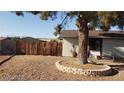 Spacious backyard with wood fence and mature tree in a decorative rock border at 5284 Wellesley Ave, Las Vegas, NV 89122