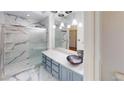 Stylish bathroom with marble walls, sleek vanity, and a glass-enclosed shower at 6944 Emerald Springs Ln, Las Vegas, NV 89113