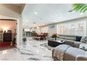 Open-concept living space with marble floors, gray sectional, dining area, and kitchen at 1920 Parkchester Dr, Las Vegas, NV 89108