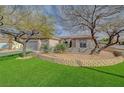 Landscaped front yard features mature trees, green grass, and a decorative stone retaining wall at 2602 Evening Sky Dr, Henderson, NV 89052