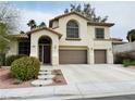 Beautiful two-story home with an arched entryway, lush landscaping, and a spacious driveway leading to a three-car garage at 3047 Whispering Crest Dr, Henderson, NV 89052