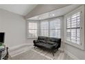 Bright sitting room featuring white shutters, wood-look floors and a comfortable black futon couch at 5429 Painted Sunrise Dr, Las Vegas, NV 89149
