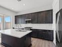 Modern kitchen with dark cabinetry, stainless steel appliances, and quartz countertops at 9032 Skye Canyon Ranch St, Las Vegas, NV 89166