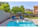 Inviting backyard pool featuring lounge chairs, umbrellas, lush greenery, and mountain views in a private setting at 10288 Grizzly Forest Dr, Las Vegas, NV 89178