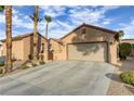 Beige single-story home boasting a long driveway, a two-car garage, and desert landscaping at 2140 Idaho Falls Dr, Henderson, NV 89044