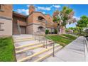 A multi-story condo building featuring a well-maintained lawn, landscaping, and a sidewalk for access at 221 Mission Catalina Ln # 202, Las Vegas, NV 89107