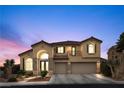 Charming two-story home with arched entry, stone accents, and a three-car garage at dusk at 4105 Falcons Flight Ave, North Las Vegas, NV 89084
