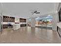 Open-concept living space with modern kitchen, large windows overlooking a backyard pool, and neutral tile floors at 6325 Carmel Creek Ave, Las Vegas, NV 89139