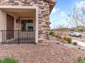 Inviting covered front porch with stone accents, iron railing, and desert landscaping creating curb appeal at 715 Pickled Pepper Pl, Henderson, NV 89011