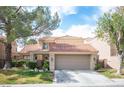 Charming two-story home featuring a tile roof, mature trees, well-manicured landscaping, and an attached two-car garage at 7566 Spanish Bay Dr, Las Vegas, NV 89113