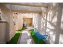 Inviting front entrance featuring artificial turf, a blue bench, and a walkway leading to a wood door at 7566 Spanish Bay Dr, Las Vegas, NV 89113
