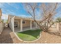 Outdoor patio area features a covered space with artificial turf, complemented by stone landscaping and mature tree at 3756 Prairie Orchid Ave, North Las Vegas, NV 89081