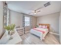 Cozy bedroom with a ceiling fan, window with floral curtains, and stylish decor on a white shelf at 4680 Peppertree St, Pahrump, NV 89061