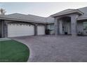Attached two-car garage with brick driveway, stone facade accents, and well maintained artificial turf at 4739 Laurel Canyon St, Las Vegas, NV 89129