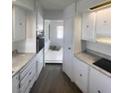 Long kitchen featuring light countertops, white cabinets, and wood-look floors at 5580 E Carey Ave, Las Vegas, NV 89156