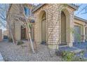 View of the front entrance showing a stone archway, decorative stone columns, and desert landscaping at 10173 Skye Saddle Ave, Las Vegas, NV 89166
