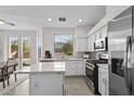 Bright kitchen featuring white cabinets, stainless steel appliances, a center island, and backyard access at 3009 Chilly Nights Ave, North Las Vegas, NV 89031