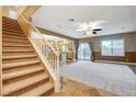 Inviting living room with staircase, tile flooring, and a ceiling fan, seamlessly flowing into the kitchen at 6828 Sumatra St, Las Vegas, NV 89166