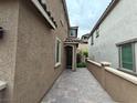 A side view of the house with an alley, showcasing the textured exterior and pathway at 8105 Switchback Run St, Las Vegas, NV 89166
