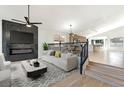 Open concept: living room flows to the kitchen and features fireplace, ceiling fan, and modern staircase at 8305 Woodland Prairie Ave, Las Vegas, NV 89129