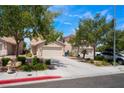 Street view of beige two-story home with mature trees and landscaping on a sunny day at 8872 Perfect Diamond Ct, Las Vegas, NV 89129
