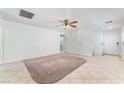Neutral living room with a ceiling fan, tile flooring, a large carpet, and access to the staircase at 8872 Perfect Diamond Ct, Las Vegas, NV 89129