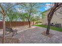 The backyard is a serene outdoor space with a stone patio, lush green lawn, and mature trees at 10223 Aragon Crown Rd, Las Vegas, NV 89135