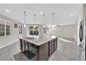 Bright kitchen featuring an island, stainless steel appliances, tile flooring, and modern pendant lighting at 10223 Aragon Crown Rd, Las Vegas, NV 89135