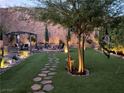 Beautiful backyard featuring stone pathways, artificial grass, a fire pit, mature trees and an outdoor living area at 176 Brighton Hills Ave, Henderson, NV 89002