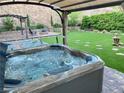 Inviting backyard featuring a hot tub, seating area, fire pit, artificial grass, and mature landscaping at 176 Brighton Hills Ave, Henderson, NV 89002