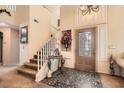 Inviting foyer with a decorative tile floor, staircase, and an elegant chandelier, offering a warm welcome at 28 Birkdale Dr, Henderson, NV 89074