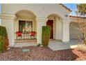 Covered front porch with cozy seating area, decorative plants, and arched entryway at 280 Pear Meadow St, Henderson, NV 89012