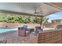 Cozy covered patio featuring comfortable wicker furniture, a fire pit, and views of the pool and backyard at 7420 Zonal Ave, Las Vegas, NV 89131