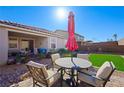 Inviting backyard featuring artificial grass, a patio area with a table and chairs, and low-maintenance landscaping at 984 Brilliant Meadow Ave, North Las Vegas, NV 89086