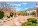 Well-manicured backyard with lush landscaping, a stone patio, and a covered pergola, perfect for outdoor living at 10508 Snyder Ave, Las Vegas, NV 89134
