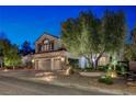 Charming stucco two-story home with a three car garage and manicured landscaping in the front yard at dusk at 2236 Midvale Ter, Henderson, NV 89074