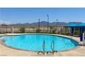 Community pool with clear blue water and mountain views on a sunny day with shade cabana and ladders for accessibility at 2629 Monte Cevedale St, Henderson, NV 89044