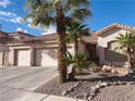 Charming home with a two-car garage and desert landscaping, including palm trees and decorative rock features at 8350 Campana Dr, Las Vegas, NV 89147