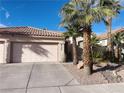 Inviting home featuring desert landscaping, mature palm trees, a red tile roof, and an attached two-car garage at 8350 Campana Dr, Las Vegas, NV 89147