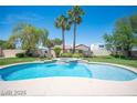Lush backyard features a pristine pool and spa, set against palm trees under a clear blue sky at 8880 W La Mancha Ave, Las Vegas, NV 89149