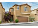 Two-story home with a two-car garage, tan stucco exterior, and green landscaping in front at 9445 Sweetwood Ave, Las Vegas, NV 89149
