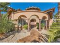 Inviting front entrance features an arched entryway with stone accents and lush tropical landscaping at 12254 La Prada Pl, Las Vegas, NV 89138