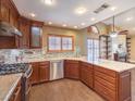 This kitchen has granite countertops, wood cabinets, a view of the living area, and stainless appliances at 1276 Spanish Armada Rd, Las Vegas, NV 89123