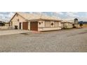 Wide shot of the exterior featuring a driveway leading to a two-car garage and car port at 1550 Tiptop Trl, Pahrump, NV 89048