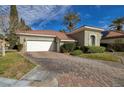 Beautiful single-story home with lush landscaping, a brick driveway, and a two-car garage at 52 Via Paradiso St, Henderson, NV 89011