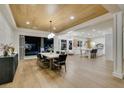 Open-concept dining area with backyard views, connected to a modern kitchen with a wood-planked ceiling at 5573 San Florentine Ave, Las Vegas, NV 89141