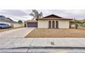 Exterior shot of a single-story home with desert landscaping, a two-car garage, and a long driveway at 6309 Fairbanks Rd, Las Vegas, NV 89103