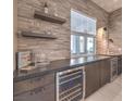 Attractive wet bar featuring stacked stone backsplash, floating shelves, and a built-in wine refrigerator at 72 Reverie Heights Ave, Henderson, NV 89011