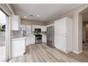 Bright kitchen featuring white cabinets, stainless steel appliances, and sliding glass door to backyard at 7836 Pinnochio Ave, Las Vegas, NV 89131